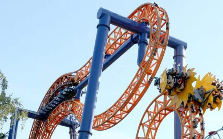 turuncu ve sarı renkte, hareket halindeyken tam ters dönmüş durumda olan bir roller coaster.